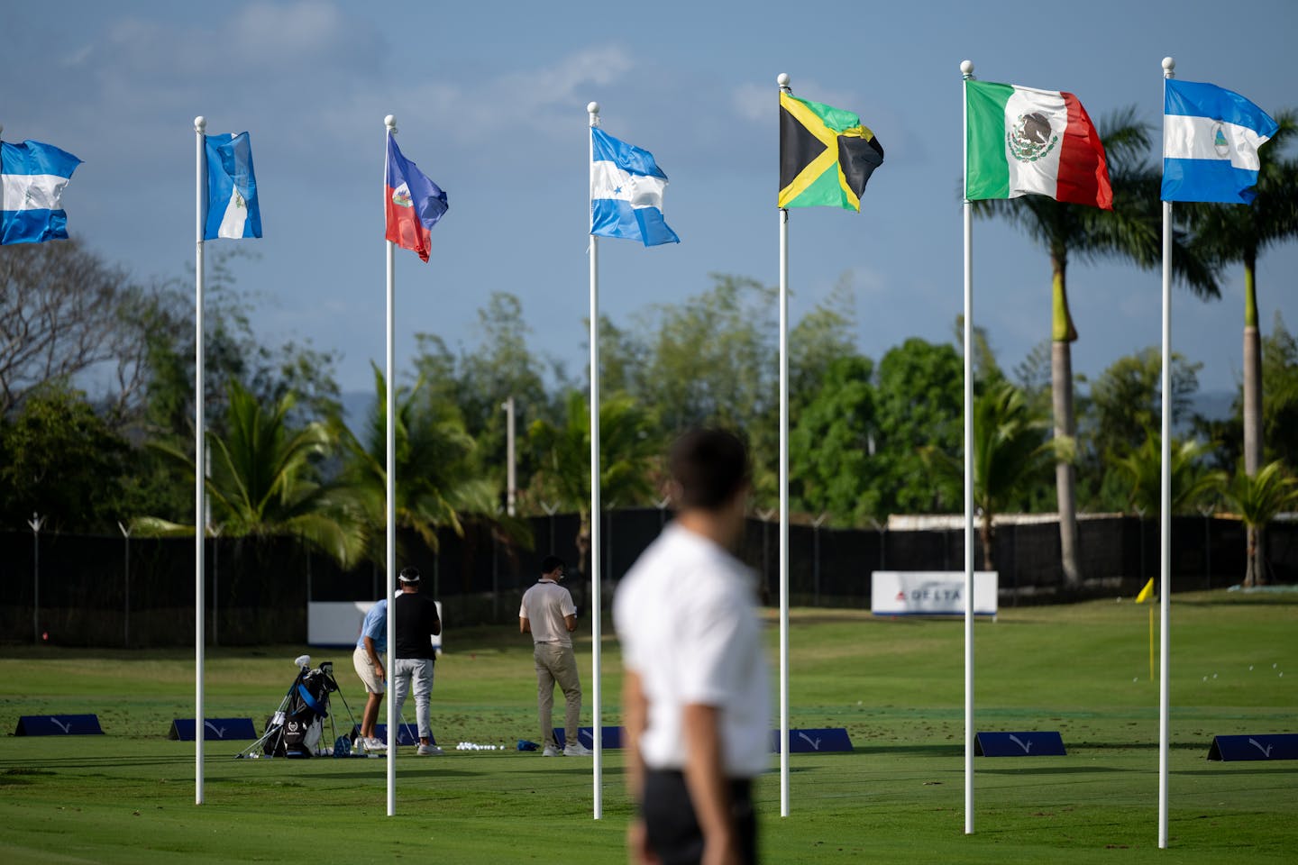 Flags fly in the breeze as golfers play on the practice range.
